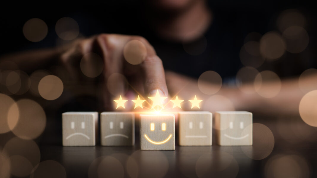 Customer review satisfaction feedback survey concept. Man Chooses a smile face on wood block cube. Questionnaire best excellent business services rating customer experience. five star good comparison,