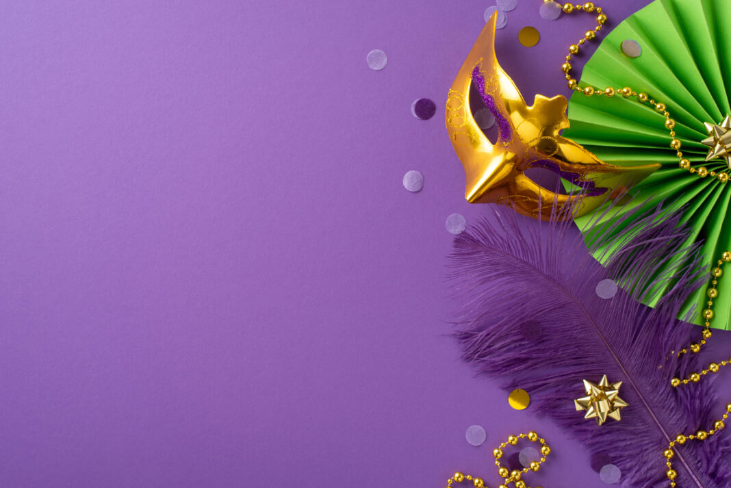 Extravagant Euphoria: Revel in grandeur of top view shot featuring lavish Venice mask, ornamental beads, feather, confetti, vivid paper fan set against purple backdrop, with space for your text